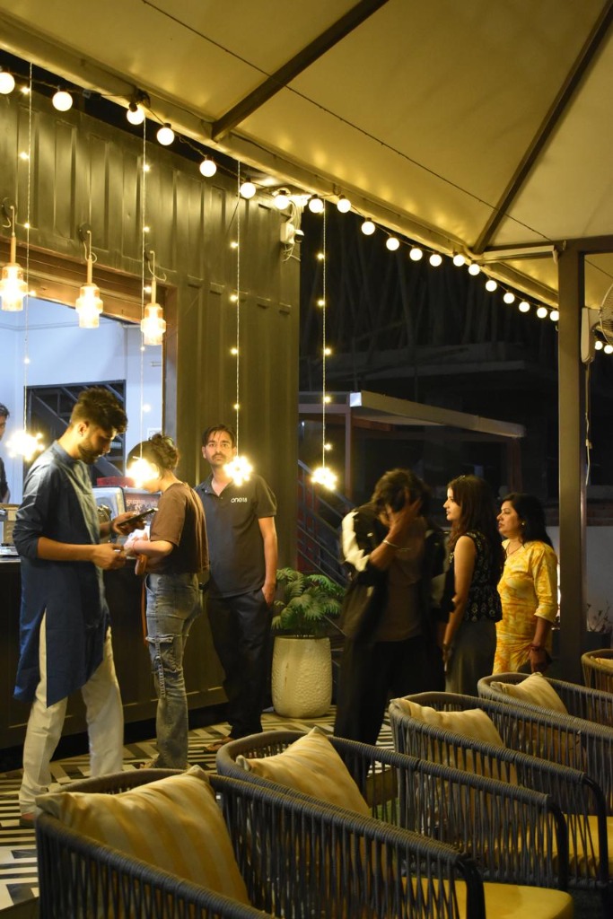 Guests socializing under warm string lights at One18 Cafe